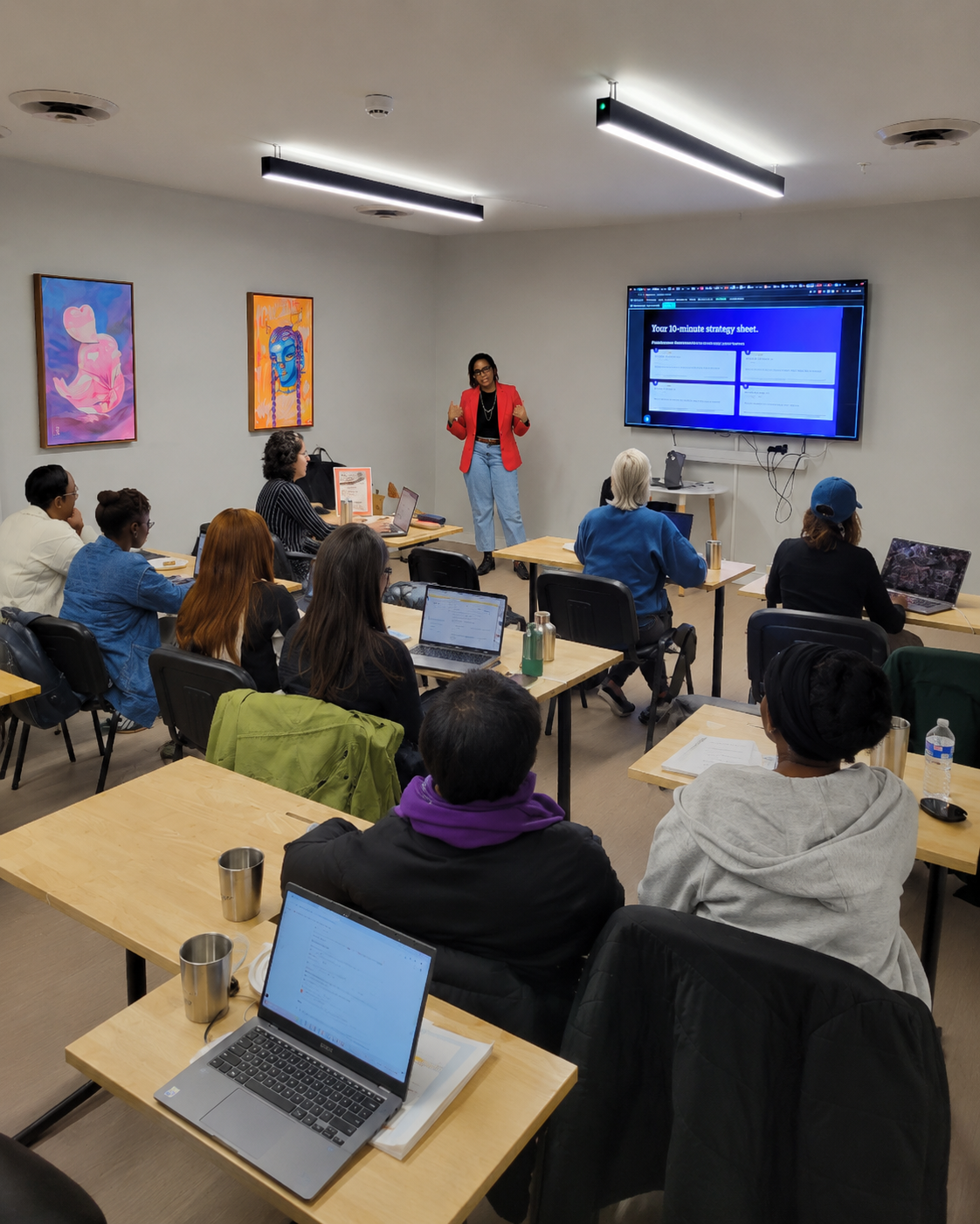 Padebi Ojomo leading a team workshop in a classroom, presenting the Omnipresence Method strategy sheet on screen